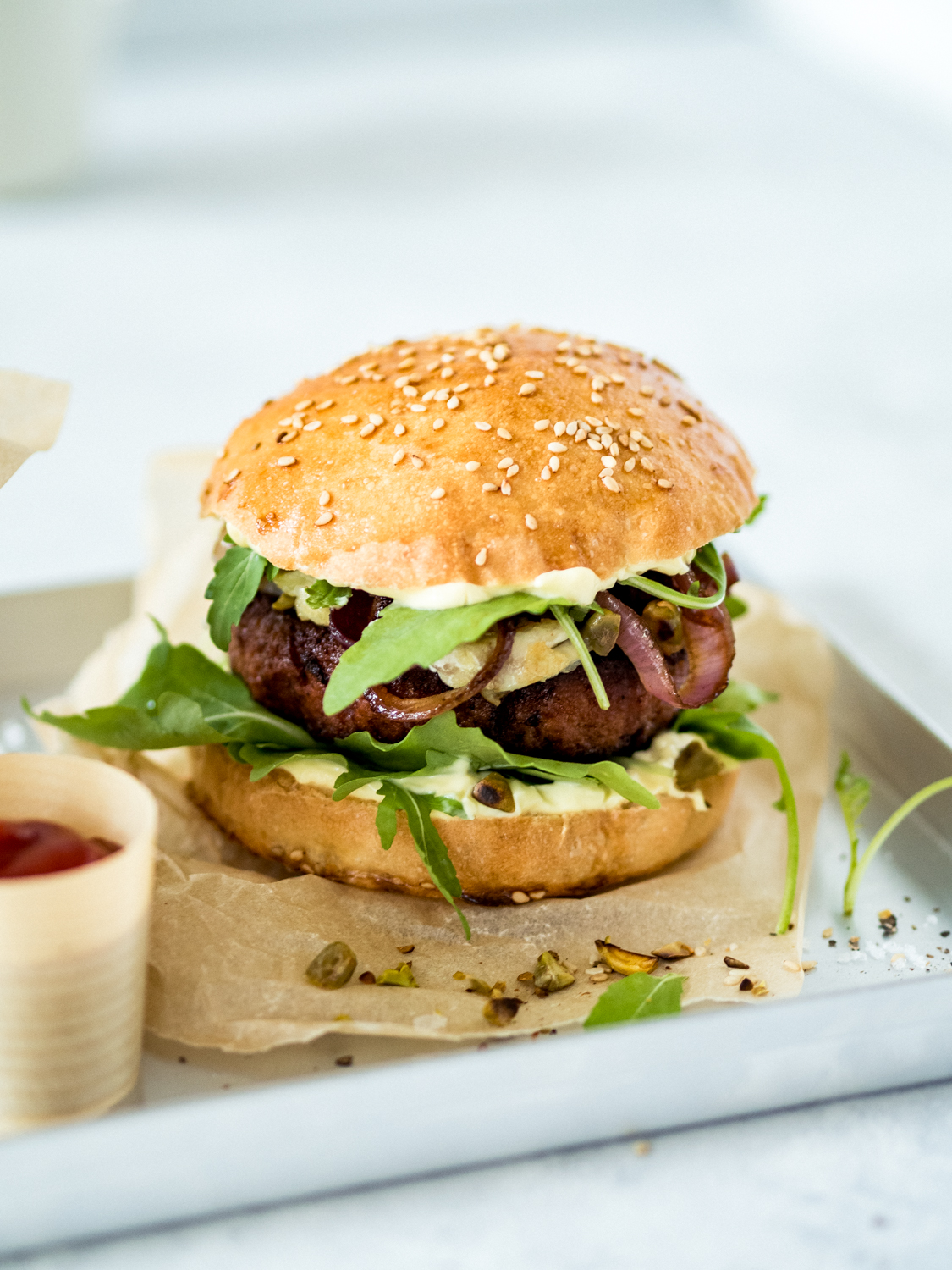 Veggie-Burger mit Pistazien-Ziegenkäse, Rucola, roten Zwiebeln und veganer Honig-Mayo